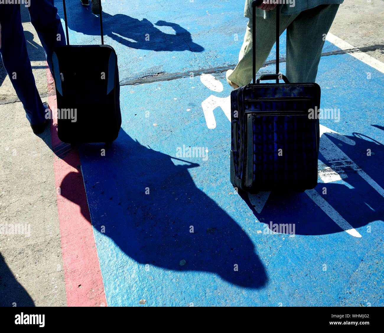 Low Section Of People Walking With Wheeled Luggage On Runway At Berlin Schonefeld Airport Stock Photo