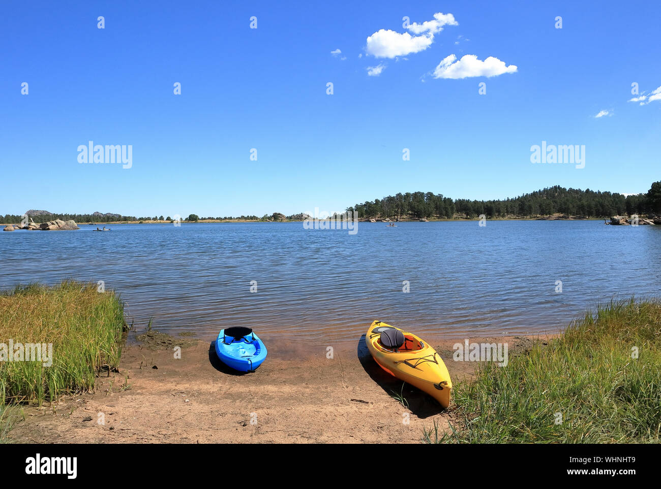 Blue and yellow kayaks are parked on the sandy beach on a sunny day on Dowdy lake, Colorado. Stock Photo