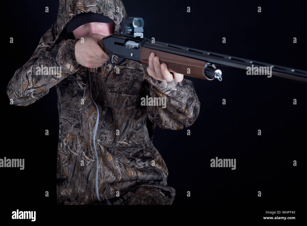 Hunter in camouflage clothing with a gun on a black background isolated