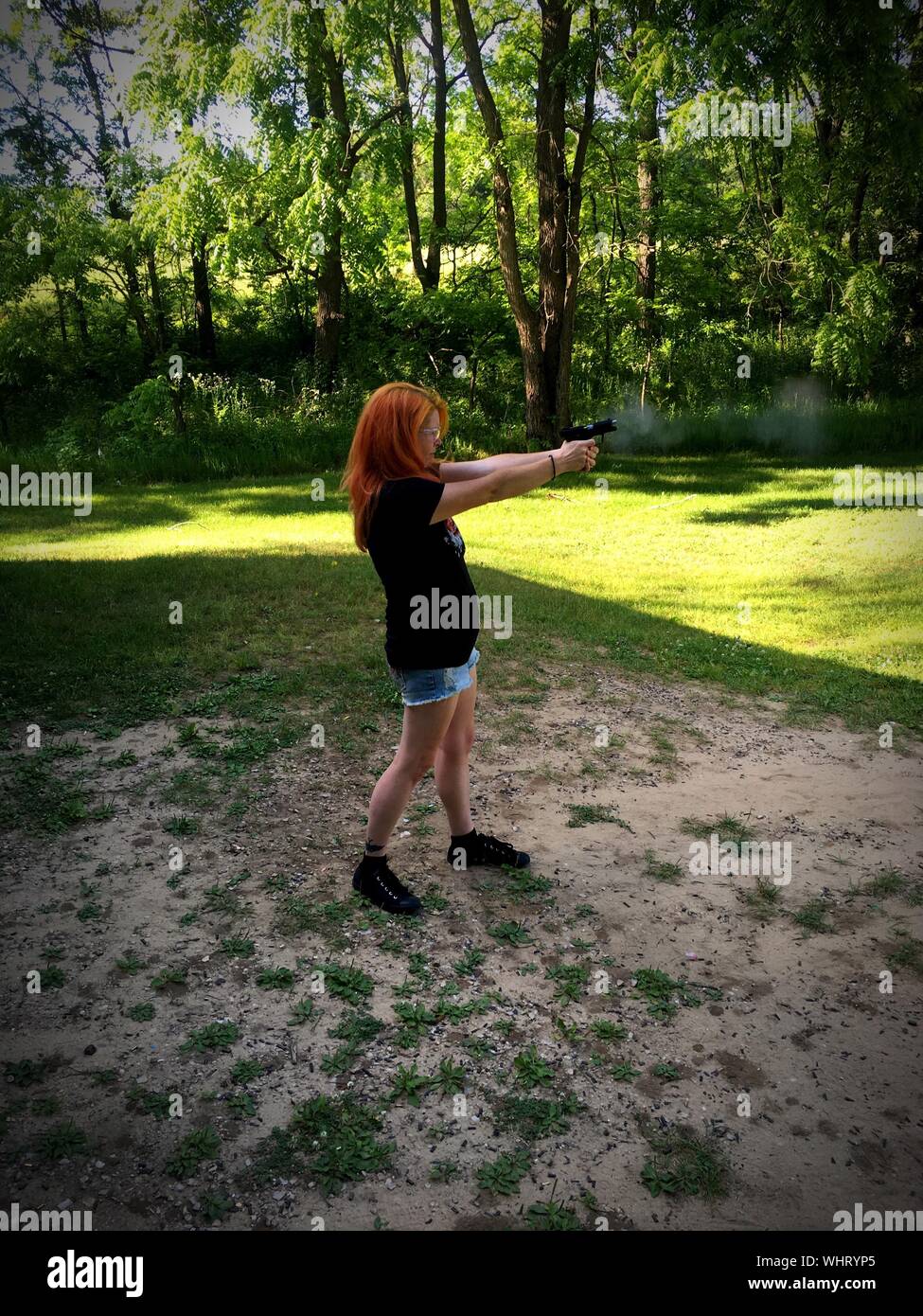 Full Length Of Woman Shooting Gun In Park Against Trees Stock Photo Alamy