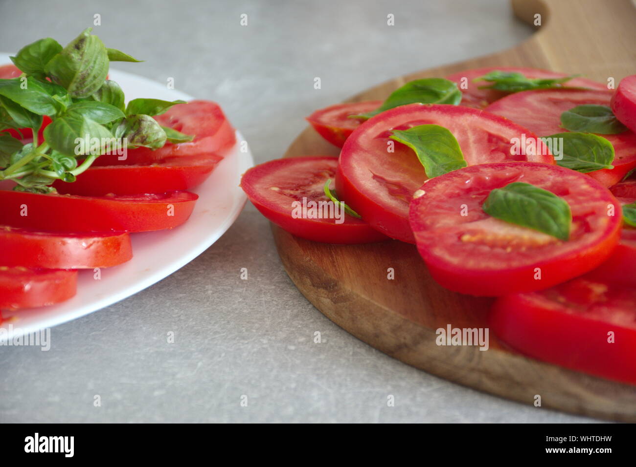 Closeup shot of the sliced tomato with basil on a plate and cutting ...