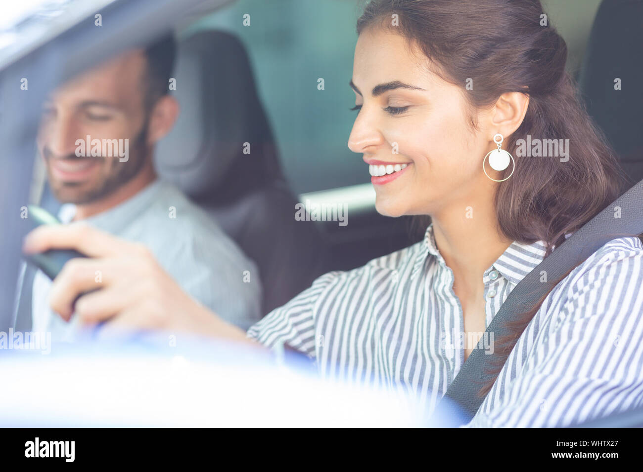 Wife wearing stylish earrings driving car sitting near husband Stock Photo