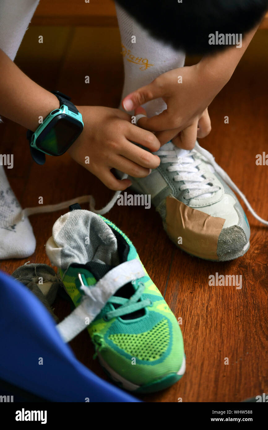 (190903) -- JINAN, Sept. 3, 2019 (Xinhua) -- Zhang Yimeng laces up his shoe before his training session in a fencing club in Jinan, east China's Shandong Province, on July 24, 2019. Zhang Yimeng, an 8-year-old primary school pupil in Jinan, started to learn fencing in 2017. At the begining, he was attracted by the cool fencing equipment on the enrollment poster. After training for almost 2 years, he has become obsessed with fencing and has achieved good results in various levels of children's fencing games in the country. 'We don't know how far he can go in fencing, but he becomes more self-re Stock Photo