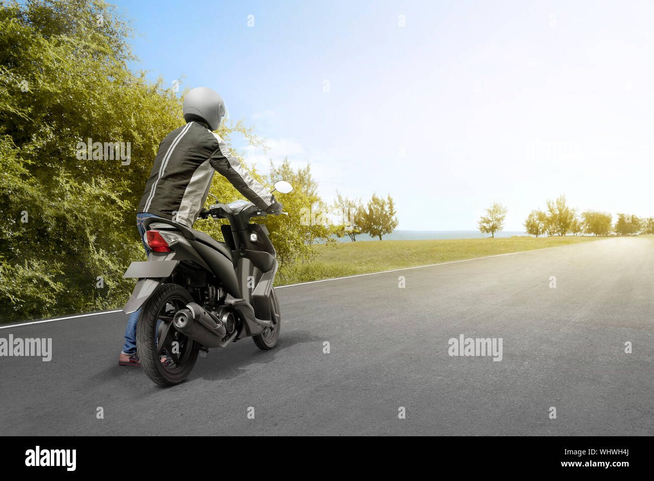 Rear view of Asian motorcycle taxi man pushes his motorcycle on the