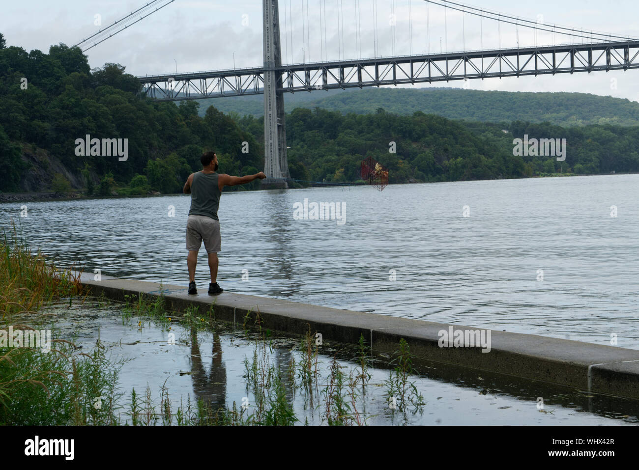 A fisherman uses a baited trap to fish for blue crabs in the Hudson River near the Bear Mountain Bridge. Sept. 2, 2019 Stock Photo
