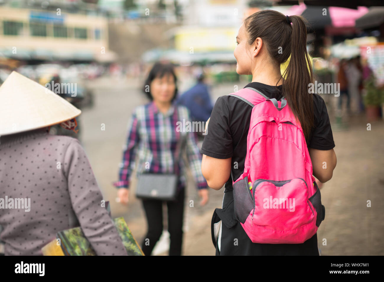 A female backpacker walking through the outdoor streetmarket, shopping. Exploration and adventure. Stock Photo