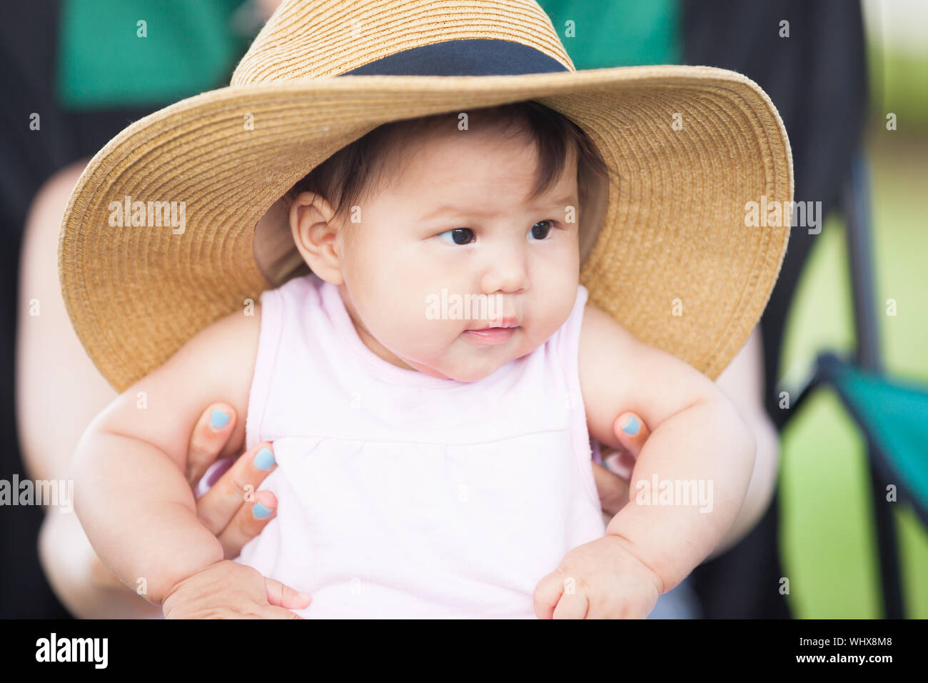 Close up shot of asian 1yo baby wearing oversized hat. Stock Photo