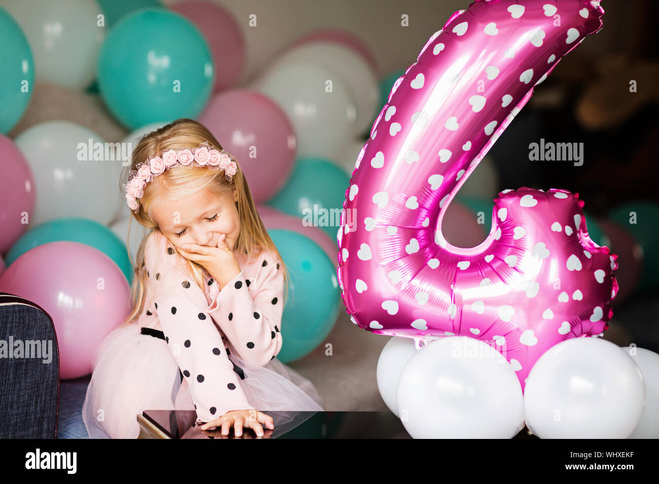 Indoor shot of pretty joyful little girl with blonde hair looking