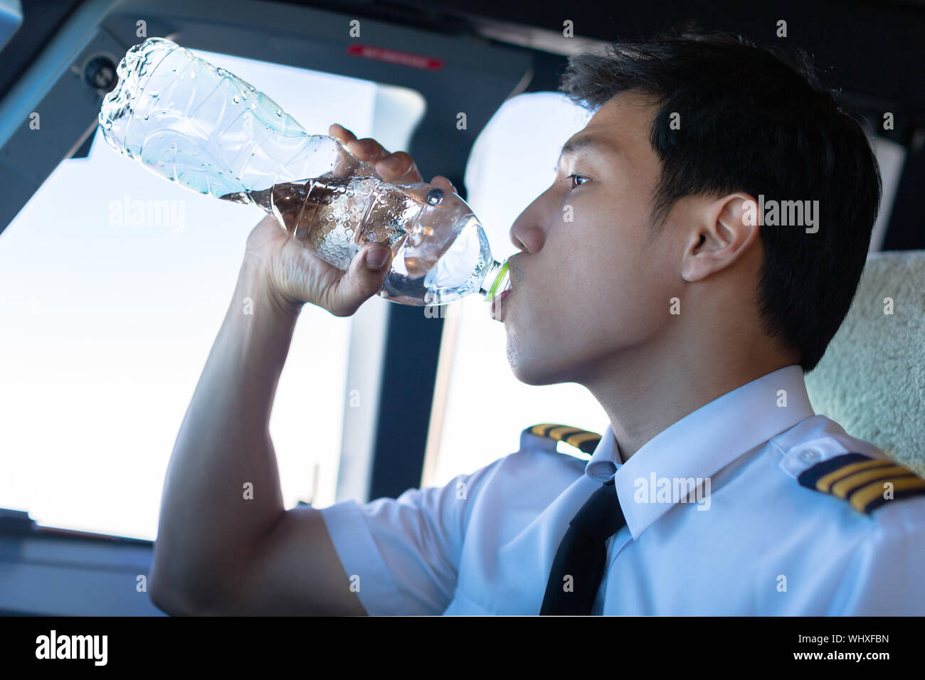 Pilot man drinking water in the airplane. Stock Photo