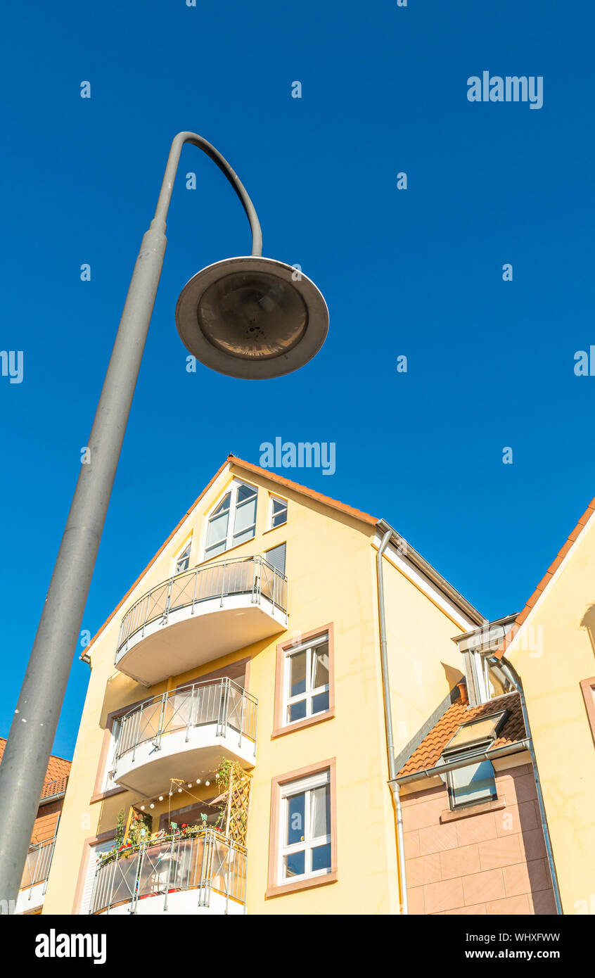 Street lamp under a residential building. Yellow building facade. Large windows in the apartment. Under a blue sky. Stock Photo