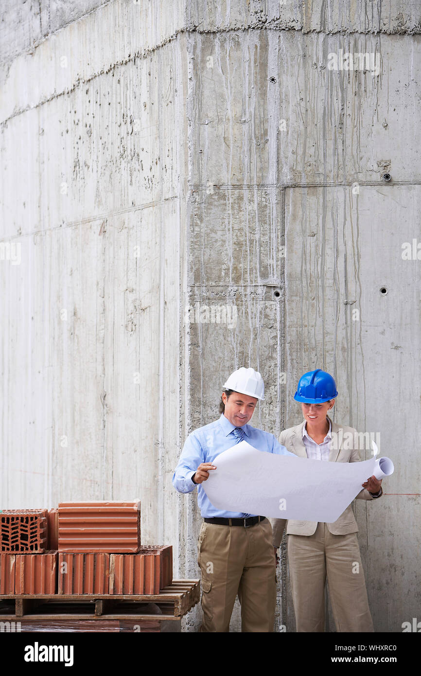 Architect and construction manager reading blueprint at site Stock Photo