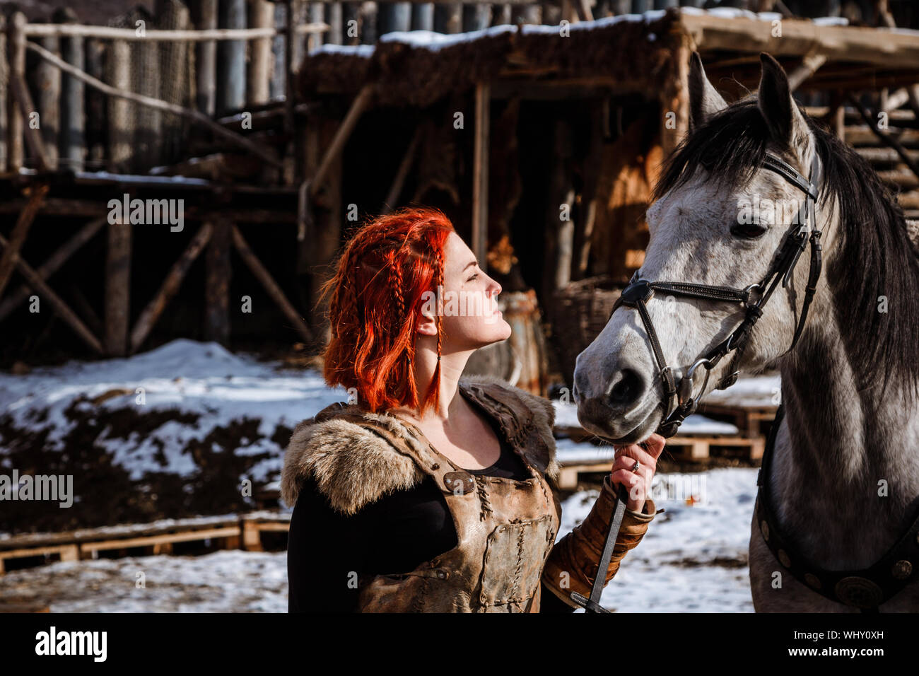 Red-haired woman with a faithful horse preparing for battle Stock Photo
