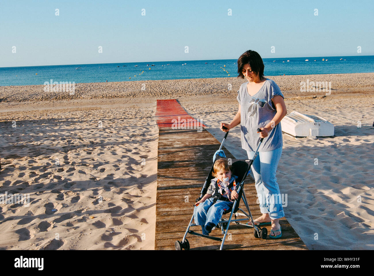 Mother With Son In Baby Stroller At Beach Stock Photo