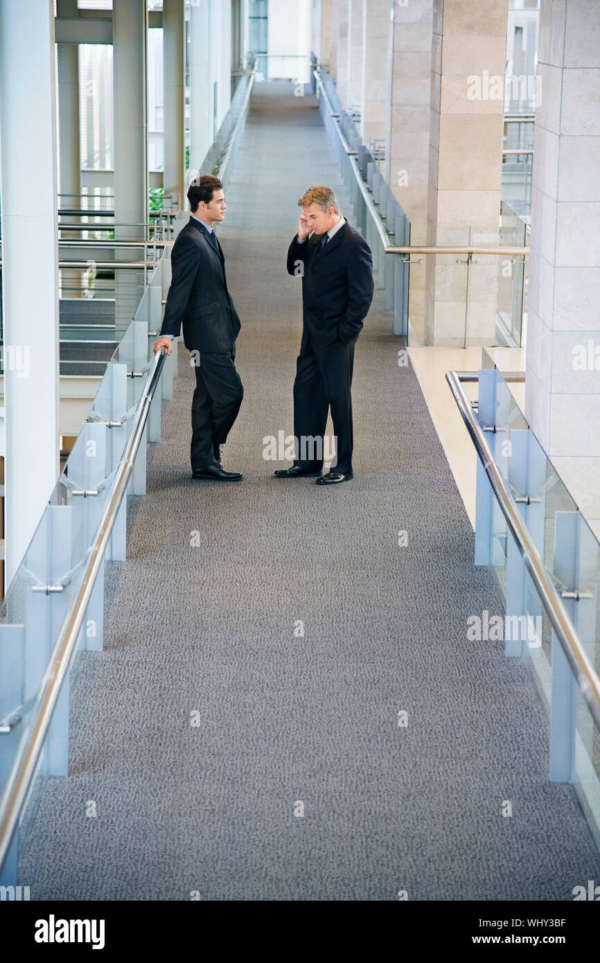 Side view of businessmen standing in office hallway Stock Photo - Alamy