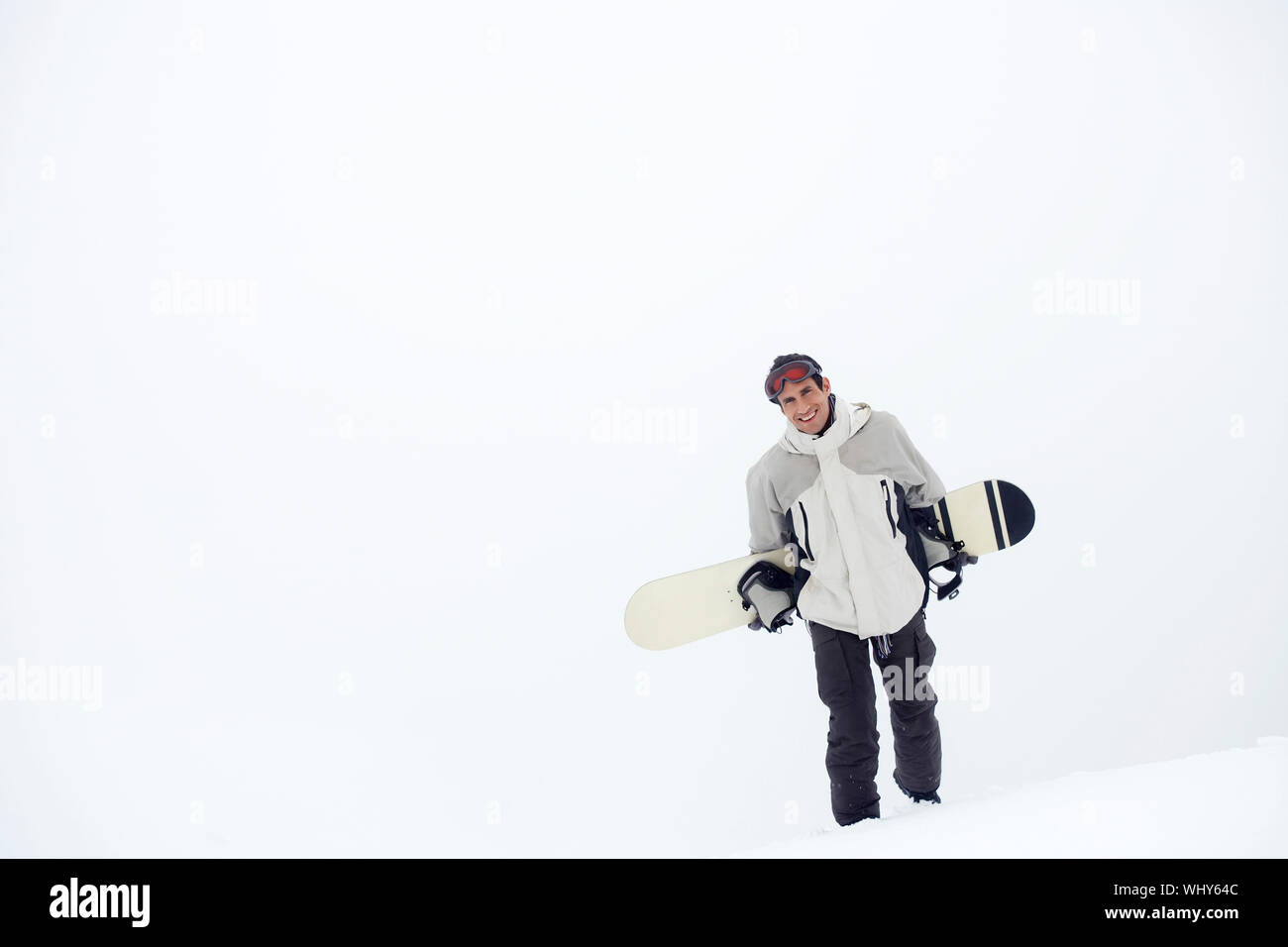 Portrait of a young man walking with snowboard in snow Stock Photo - Alamy