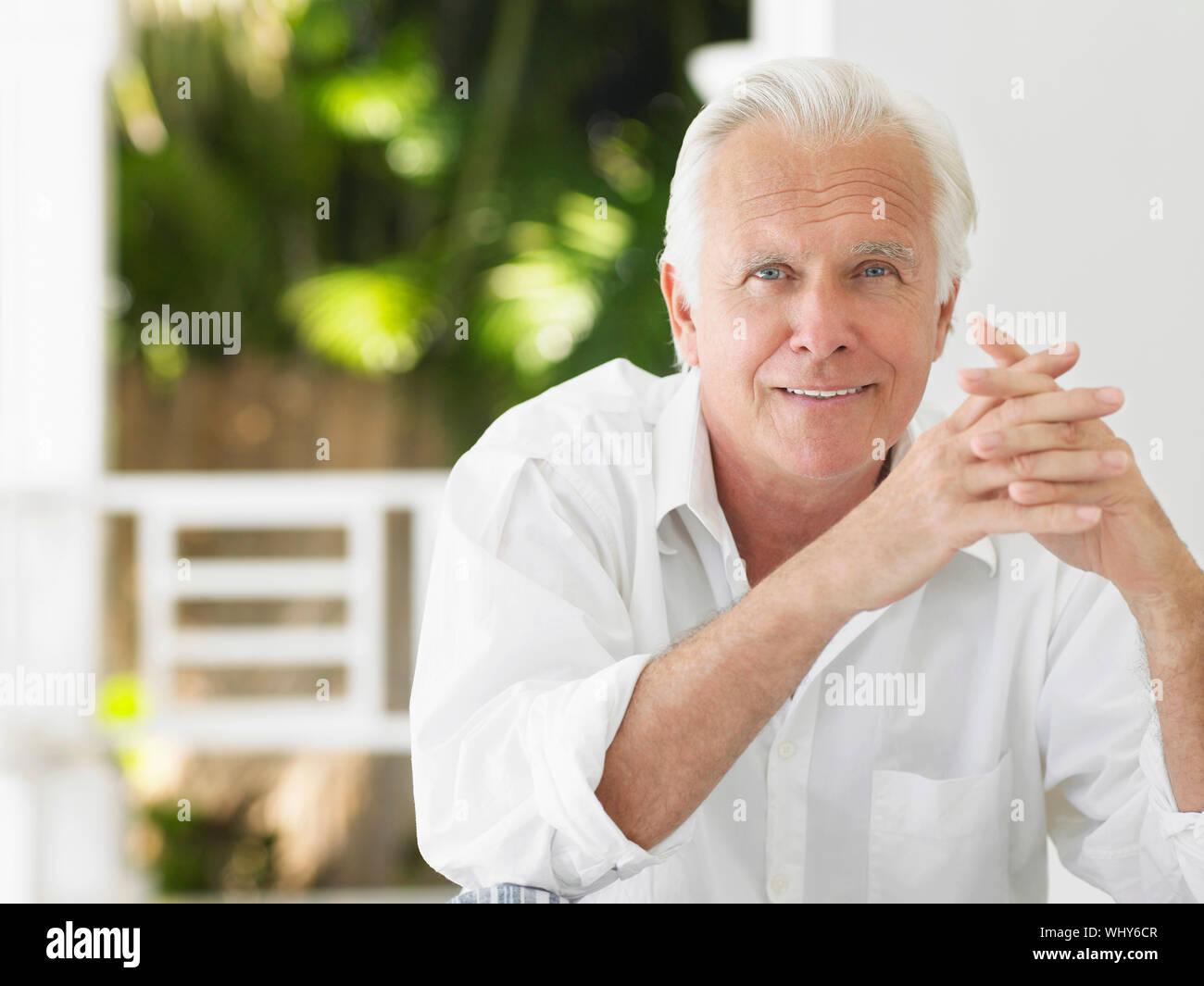 Portrait of a smiling mature man sitting on verandah Stock Photo - Alamy