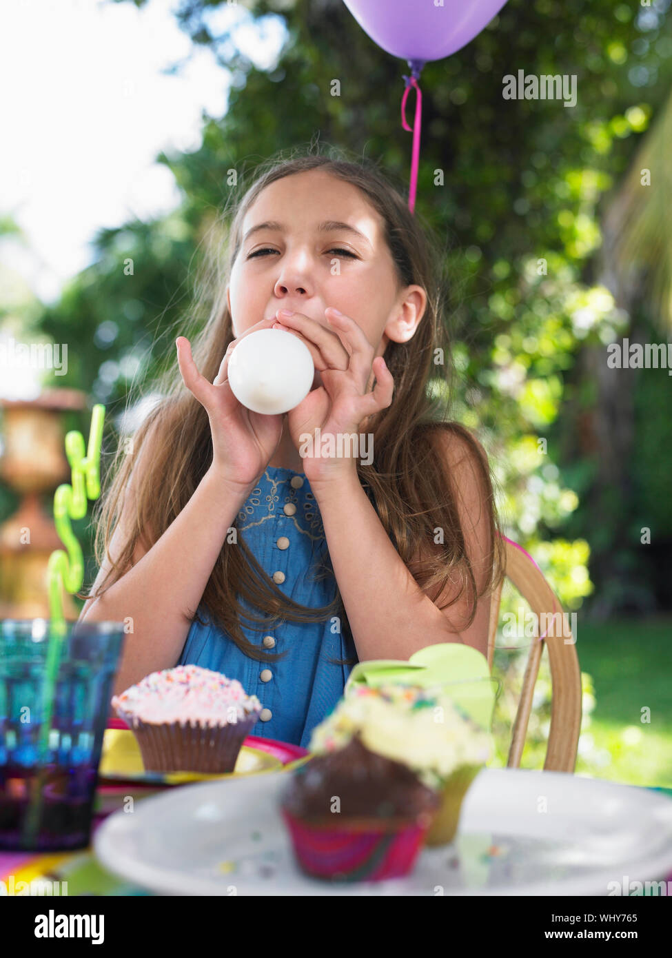Young girl blowing up balloon at the outdoor birthday party Stock Photo ...