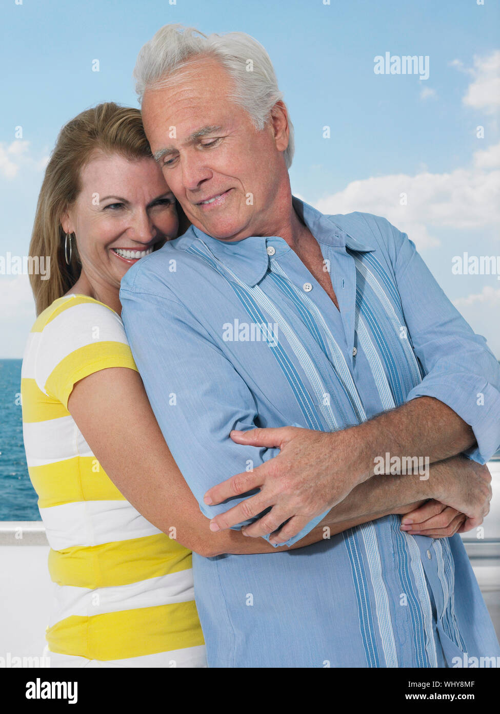 Happy middle aged woman embracing man from behind on yacht Stock Photo