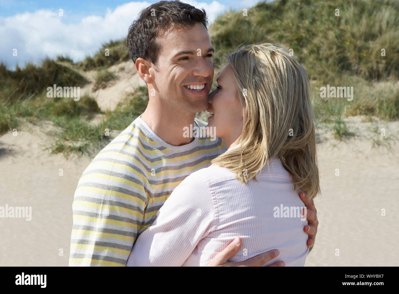 Loving young man embracing woman on beach Stock Photo - Alamy