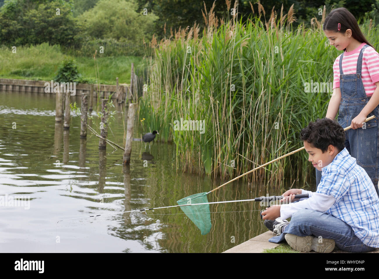 Happy brother and sister fishing in lake Stock Photo - Alamy