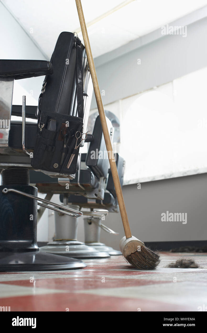 Broom beside barber's chair in hair salon Stock Photo Alamy