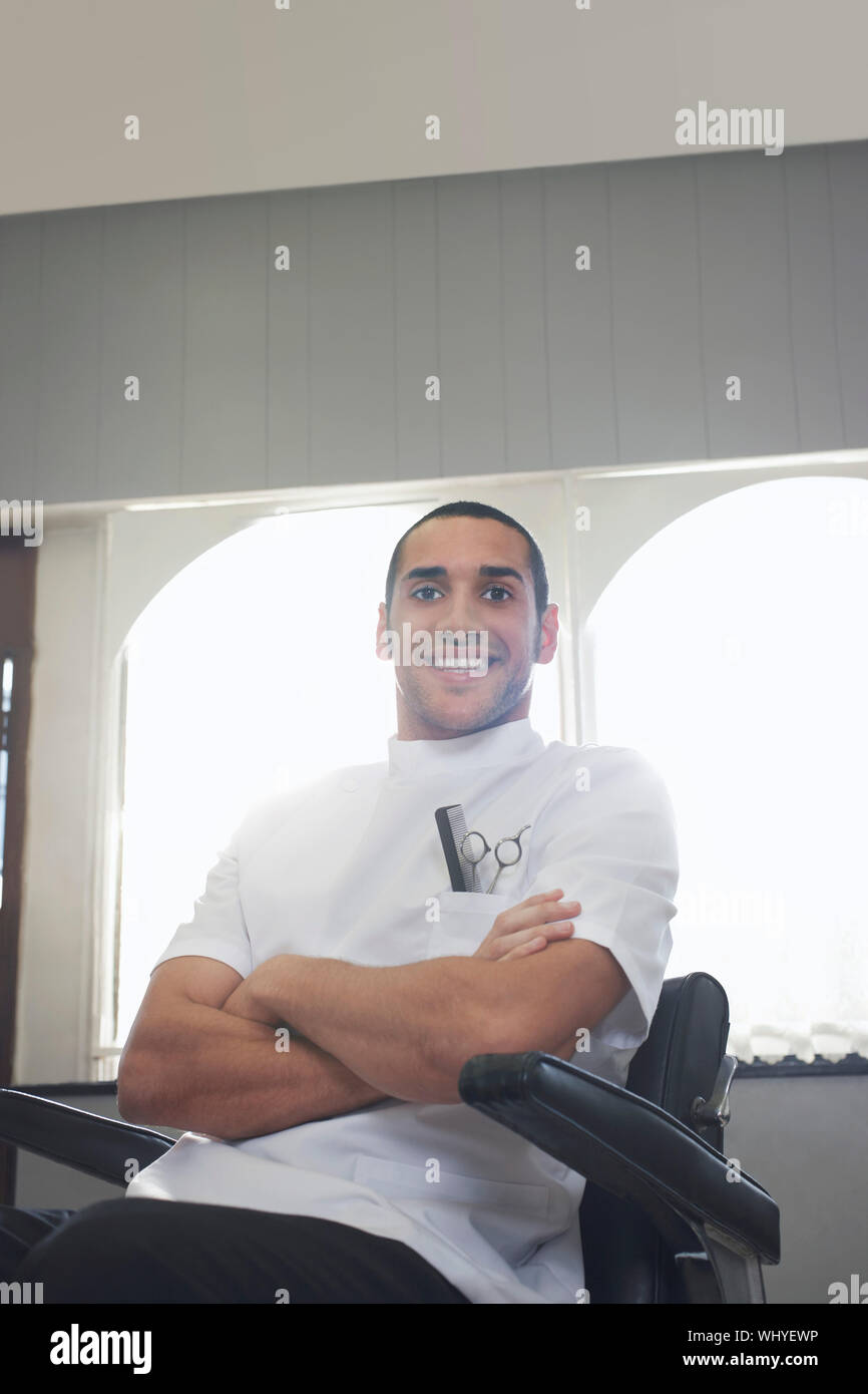 Portrait Of Young Barber In Uniform Smiling At Hair Salon Stock