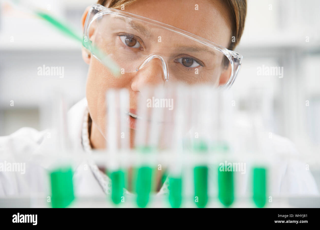 Closeup of a female scientist filling test tubes with pipette in ...