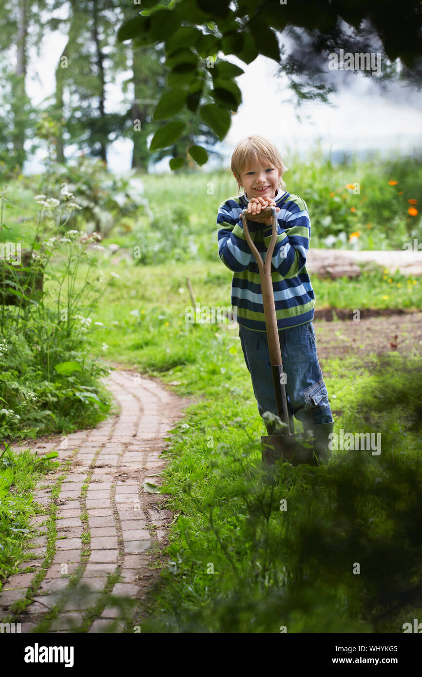 Full length portrait of a smiling young boy with spade in garden Stock ...