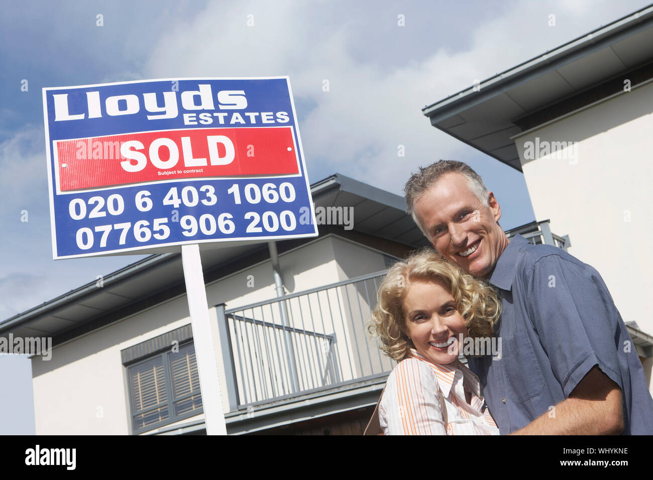 Portrait of a smiling couple by sold sign outside new home Stock Photo ...