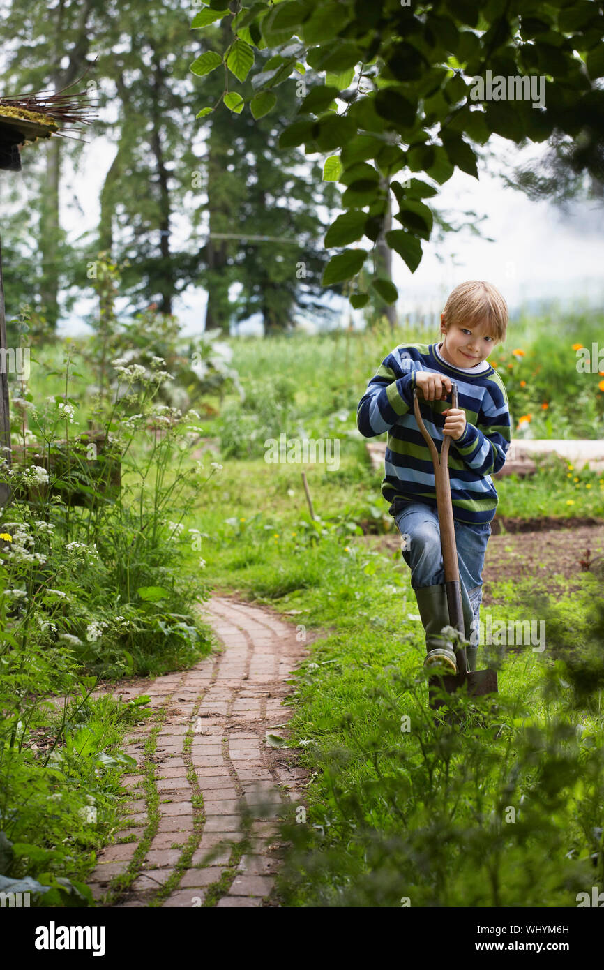 Full length portrait of a smiling young boy with spade in garden Stock ...