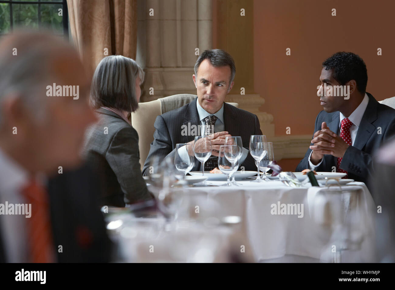 Multiethnic businesspeople sitting at restaurant table and talking Stock Photo