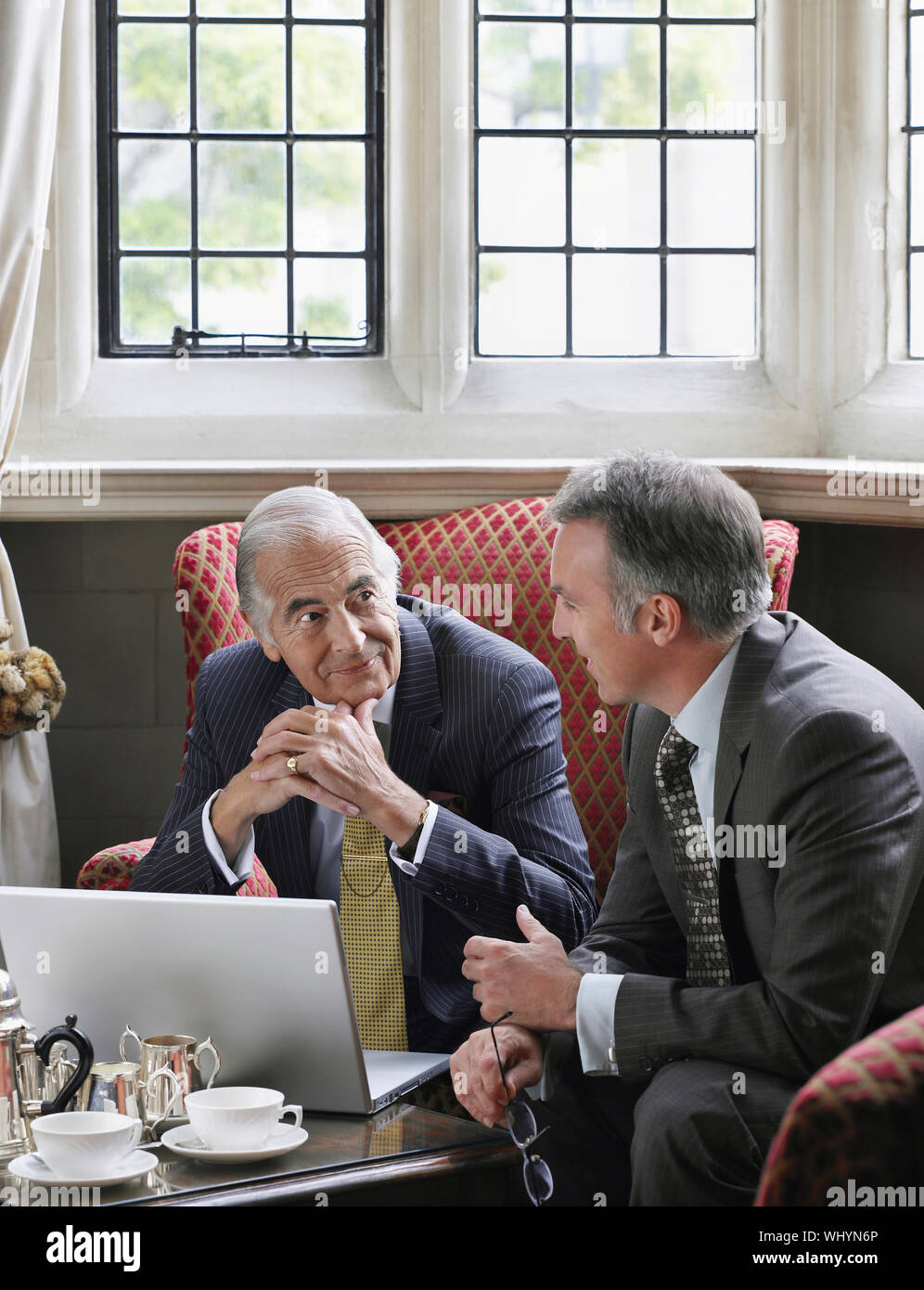 Two businessmen talking over laptop in office lobby Stock Photo - Alamy