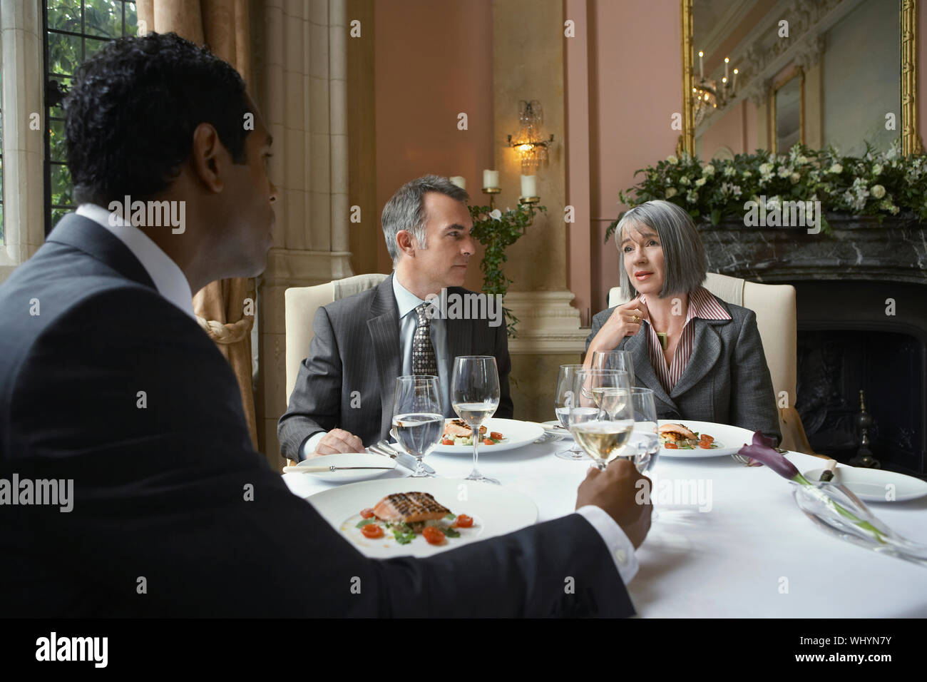 Multiethnic businesspeople sitting at restaurant table and talking Stock Photo