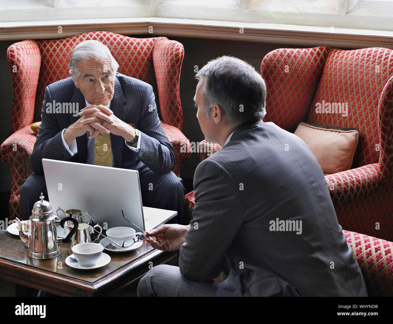 Two businessmen talking over laptop in office lobby Stock Photo - Alamy