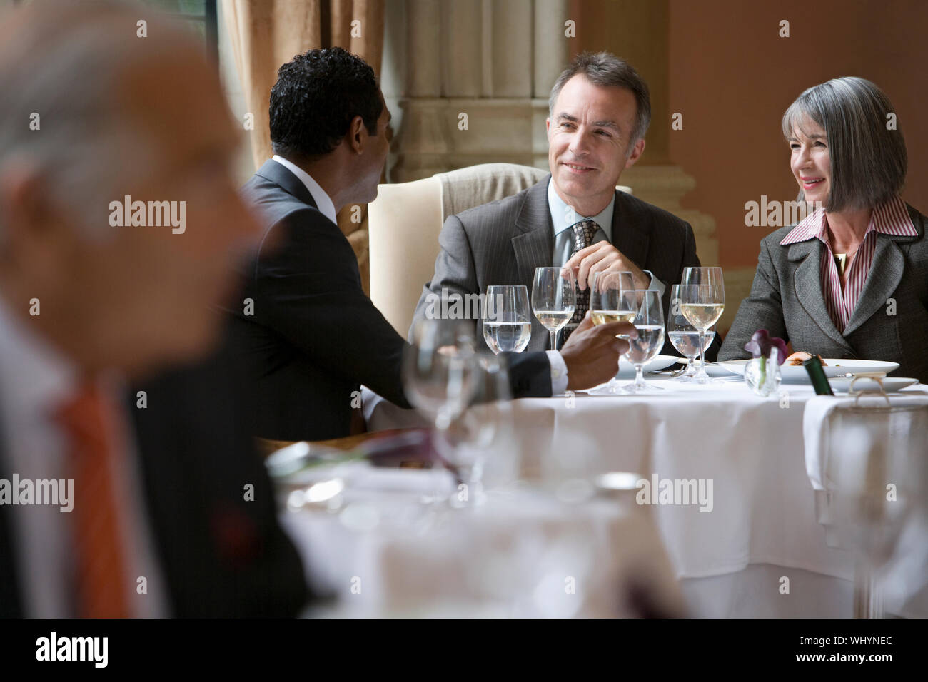 Multiethnic businesspeople sitting at restaurant table and talking Stock Photo
