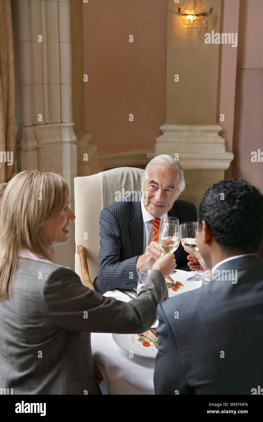 Multiethnic businesspeople toasting wineglasses at restaurant table Stock Photo