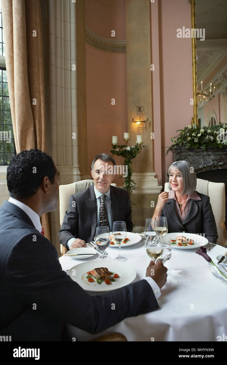 Multiethnic businesspeople sitting at restaurant table and talking Stock Photo