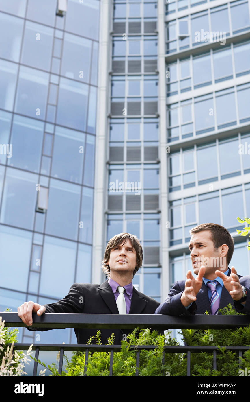 Two young businessmen talking outside office building Stock Photo - Alamy