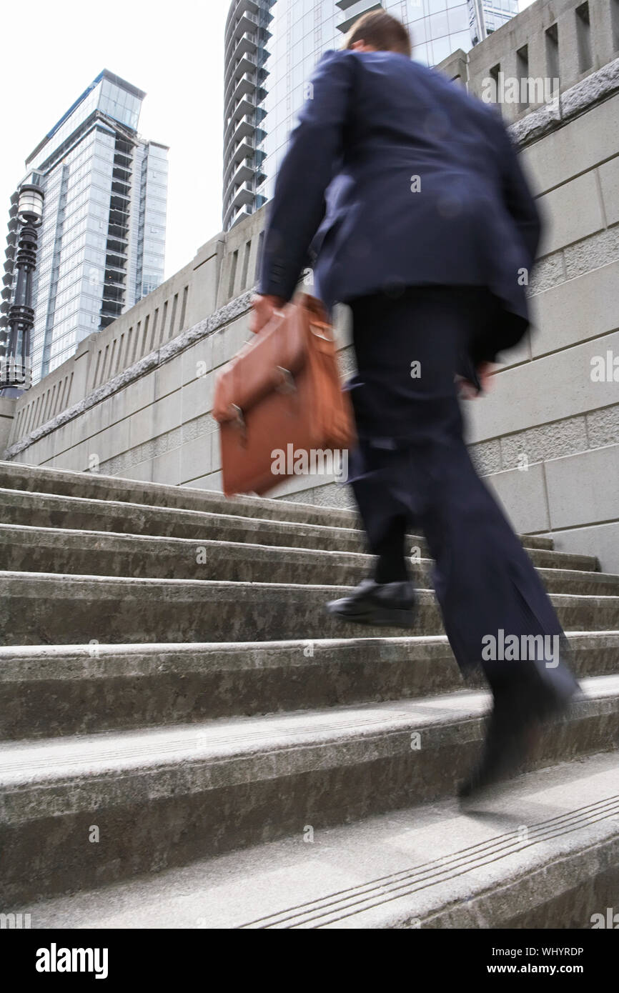 Full length rear view of a businessman with briefcase ascending steps Stock Photo