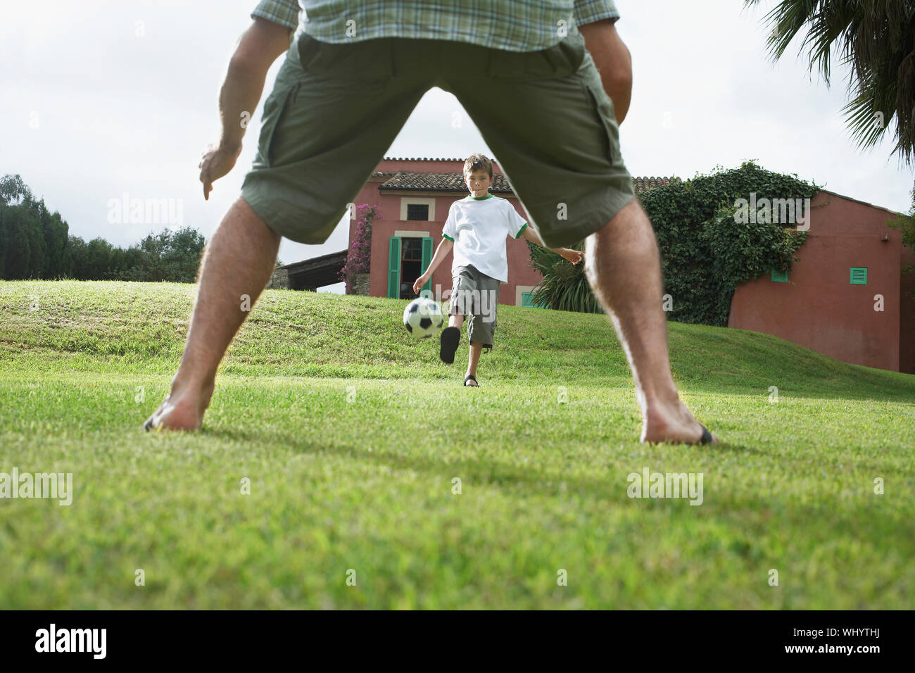 Lowsection of father with son playing football in backyard Stock Photo ...