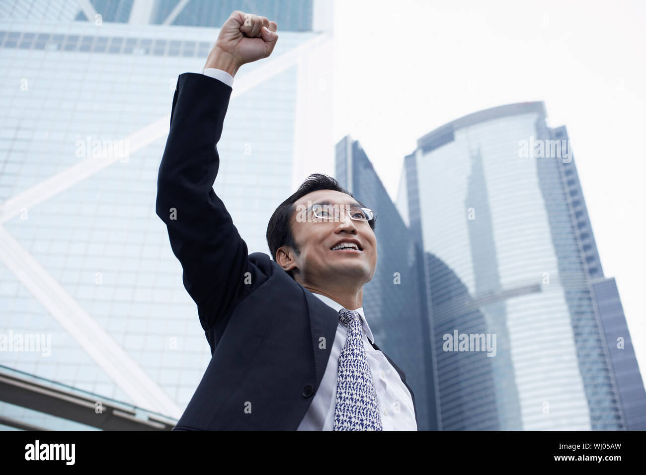 Successful businessman with arms raised outside office buildings Stock ...