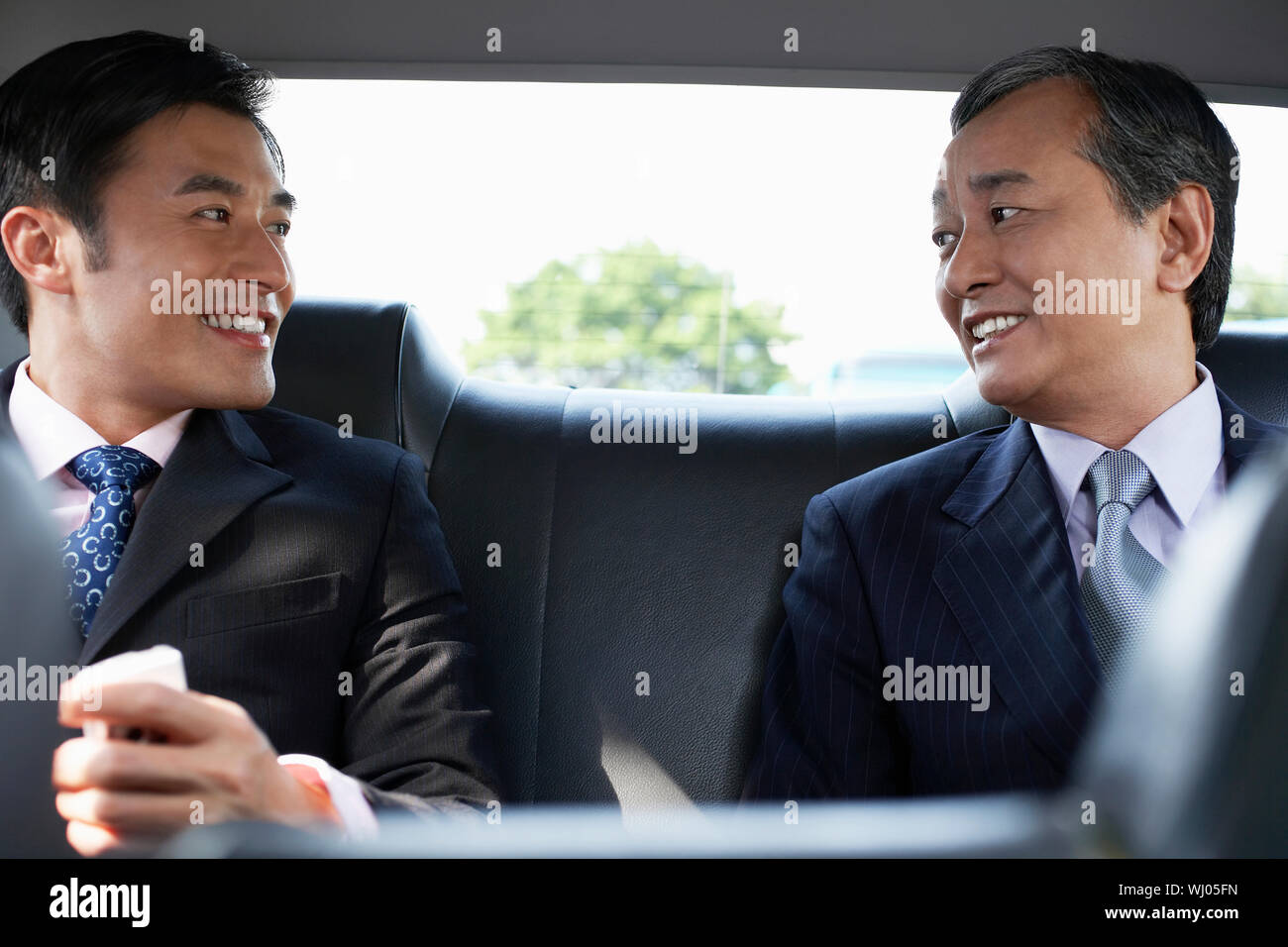 Two businessmen conversing in backseat of car Stock Photo