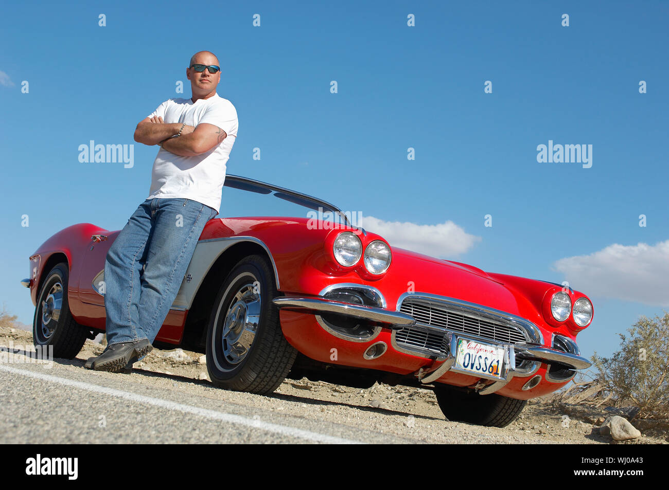 Man standing beside classic car on road Stock Photo - Alamy