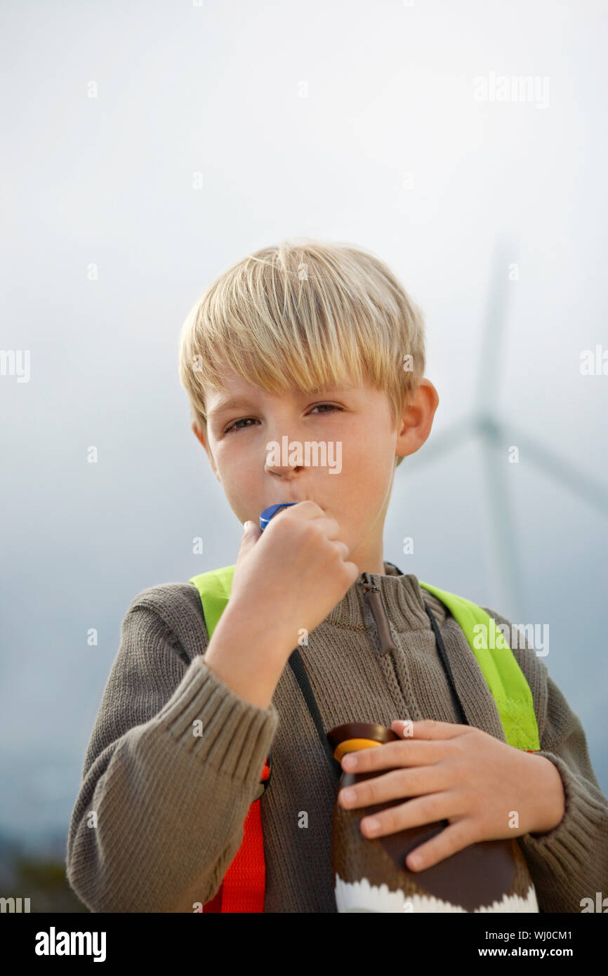 Boy (79) blowing toy whistle at wind farm, portrait Stock Photo Alamy