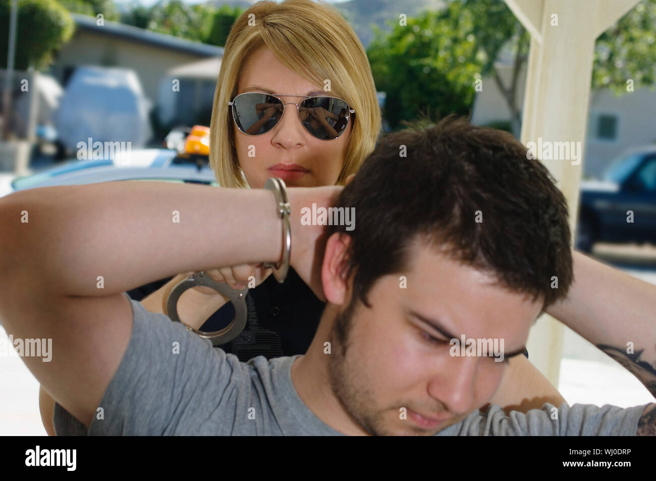 A female police officer arresting young man Stock Photo - Alamy