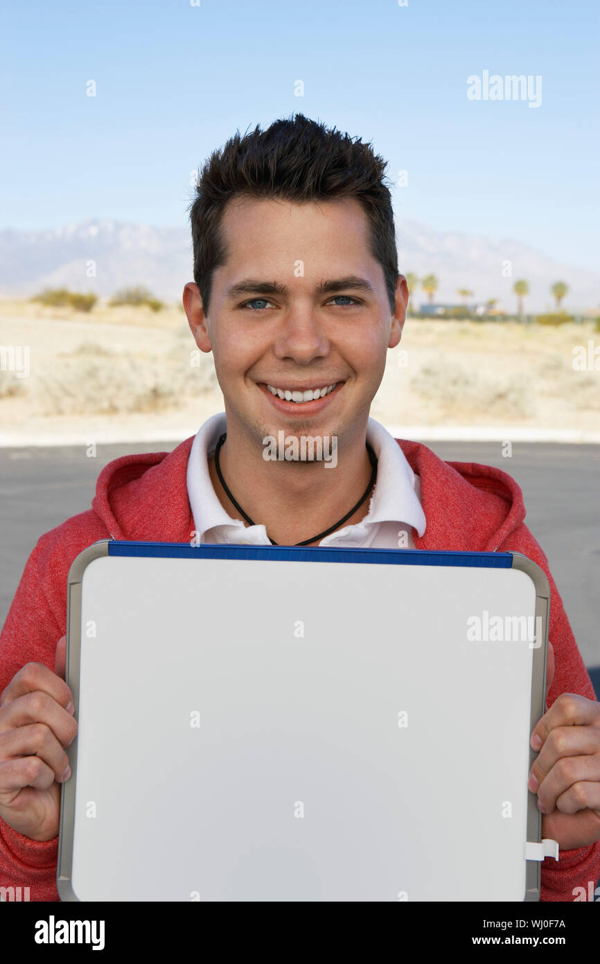Portrait of young man holding sign outdoors Stock Photo