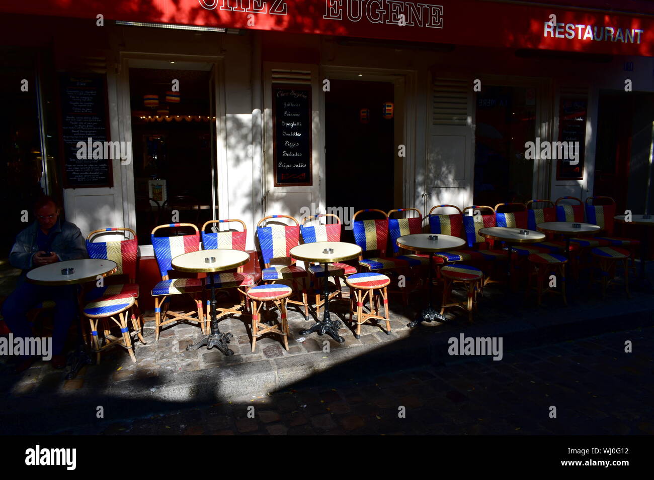 Wooden chairs with the French Flag at famous Chez Eugene cafe restaurant in Montmartre. Paris, France. August 12, 2019. Stock Photo