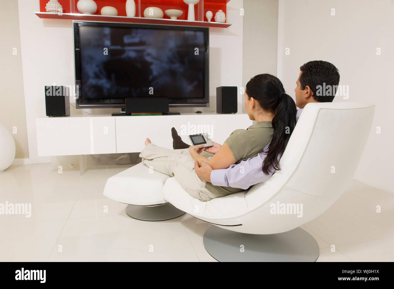 Relaxed couple sitting on a modern chair while watching television Stock  Photo - Alamy