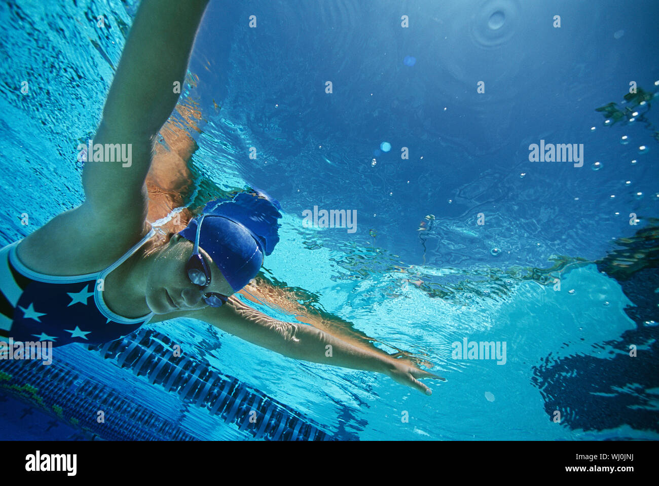 Female swimmer wearing United States swimsuit, swimming in pool Stock Photo