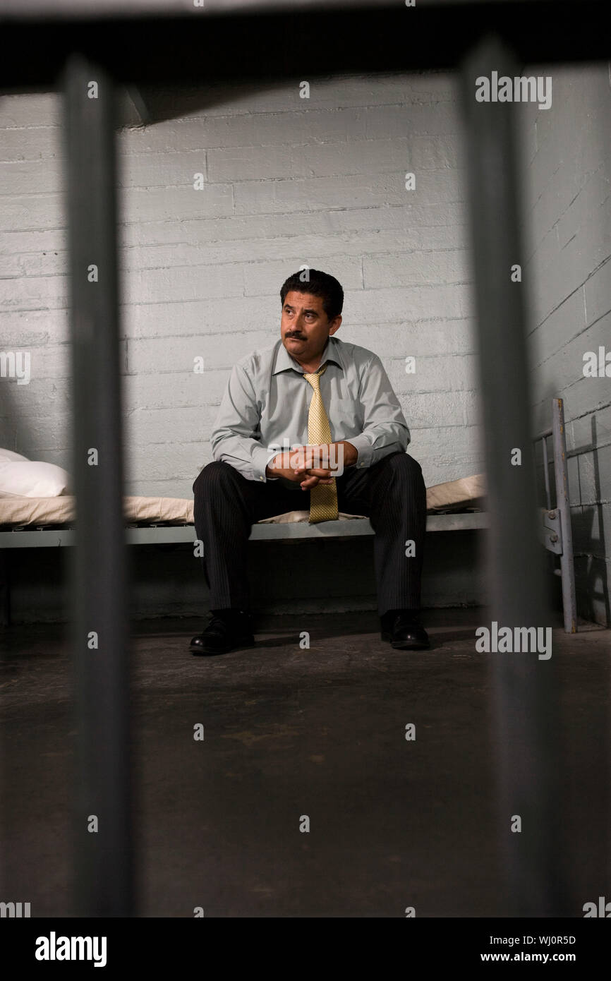 Criminal sitting on bed in jail Stock Photo Alamy